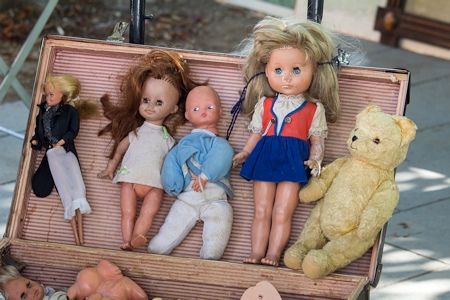 Alte Puppen, Barbies und Teddy auf einem Flohmarkttisch